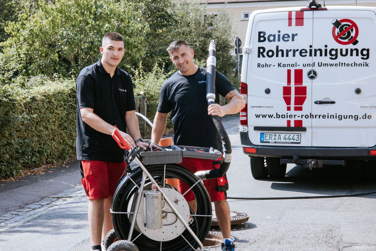 Zwei Techniker der Baier Rohrreinigung GmbH mit Fräsroboter vor dem Servicewagen